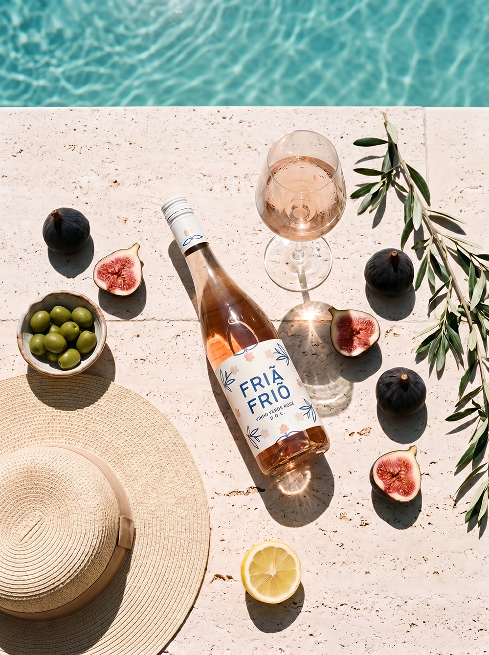 Rosé bottle styled poolside with fruit and hat